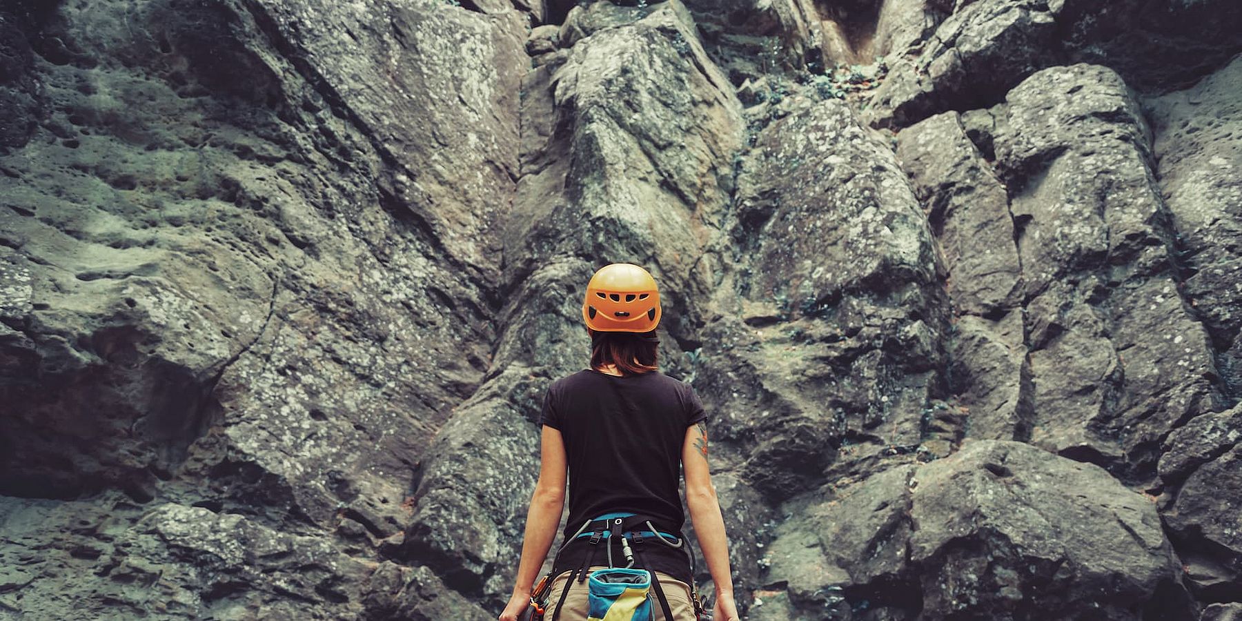 Eine Frau blickt beim Klettern die Felswand eines Klettersteigs im Zillertal nach oben